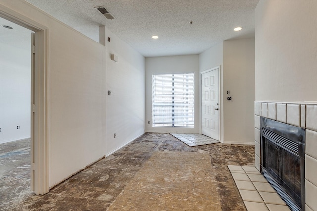 entrance foyer featuring heating unit, visible vents, a textured ceiling, and a tiled fireplace