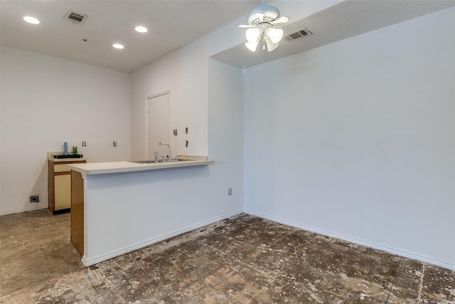 interior space with ceiling fan, light countertops, a sink, and visible vents