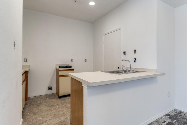 kitchen featuring a peninsula, baseboards, light countertops, and a sink