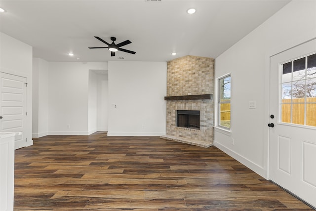 unfurnished living room featuring dark wood finished floors, vaulted ceiling, a fireplace, and ceiling fan