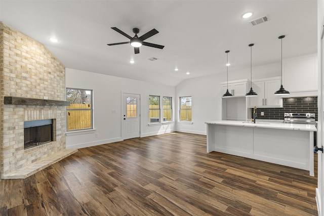 kitchen featuring lofted ceiling, visible vents, decorative backsplash, a brick fireplace, and open floor plan