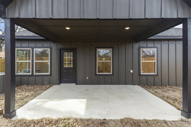 entrance to property with board and batten siding and a patio area