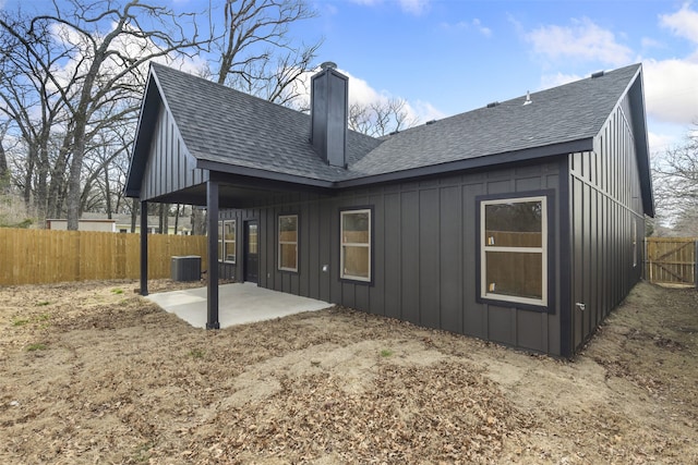 back of property featuring a patio area, a fenced backyard, a chimney, and board and batten siding