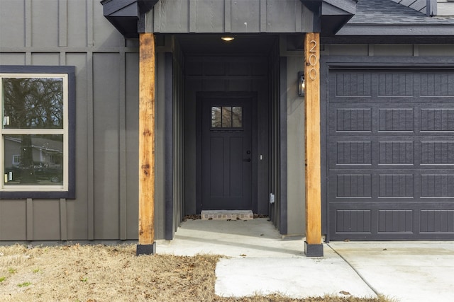 entrance to property featuring board and batten siding, a shingled roof, and an attached garage