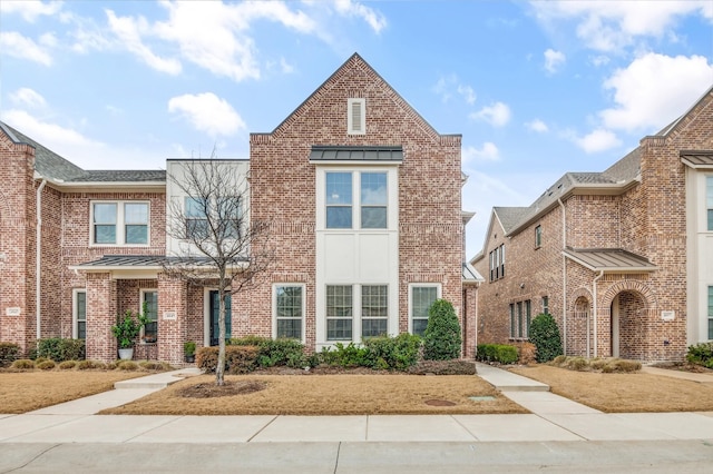 townhome / multi-family property featuring a standing seam roof and brick siding