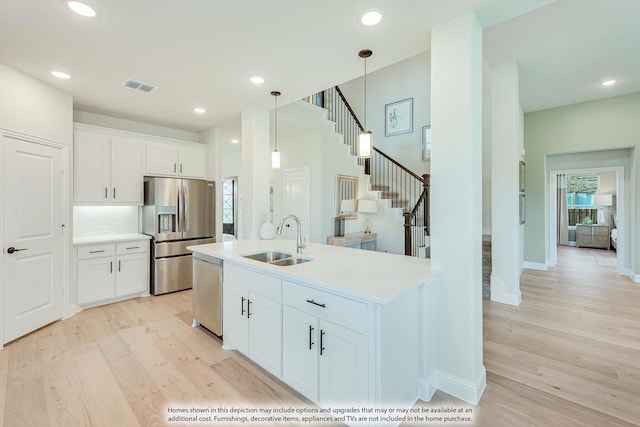 kitchen with stainless steel appliances, light countertops, visible vents, light wood-style flooring, and a sink