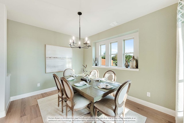 dining space featuring light wood-type flooring, an inviting chandelier, baseboards, and visible vents