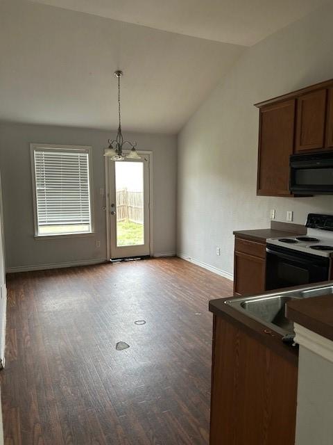 kitchen featuring black microwave, range with electric cooktop, baseboards, vaulted ceiling, and dark countertops