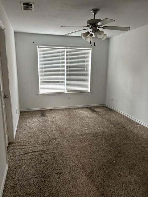 carpeted spare room with baseboards, visible vents, and a ceiling fan