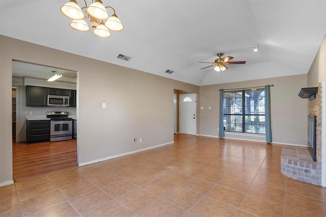 unfurnished living room with light tile patterned floors, visible vents, vaulted ceiling, and a fireplace with raised hearth