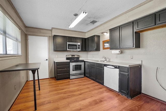 kitchen with stainless steel appliances, light wood-type flooring, a sink, and visible vents