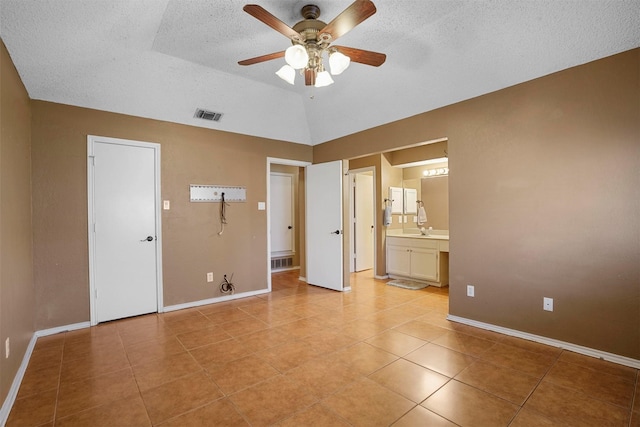 unfurnished bedroom featuring vaulted ceiling, a textured ceiling, visible vents, and baseboards