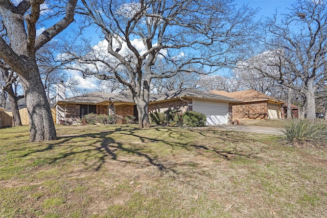 view of front of house featuring a garage, brick siding, driveway, a front lawn, and a chimney