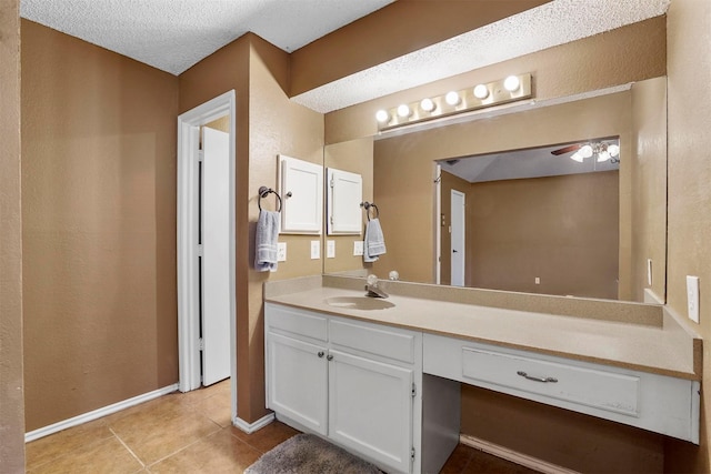 bathroom with a textured ceiling, a ceiling fan, baseboards, vanity, and tile patterned floors