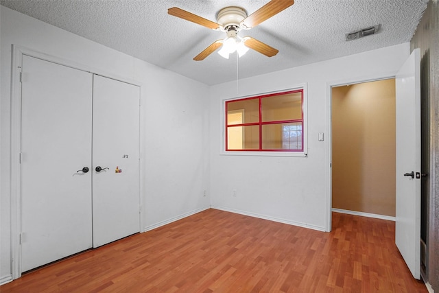 unfurnished bedroom featuring visible vents, a ceiling fan, a textured ceiling, light wood-type flooring, and a closet