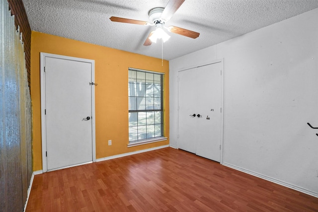 interior space featuring a textured ceiling, ceiling fan, wood finished floors, and baseboards