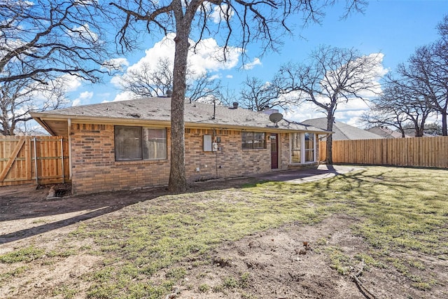 rear view of property with brick siding, a lawn, a patio area, and a fenced backyard