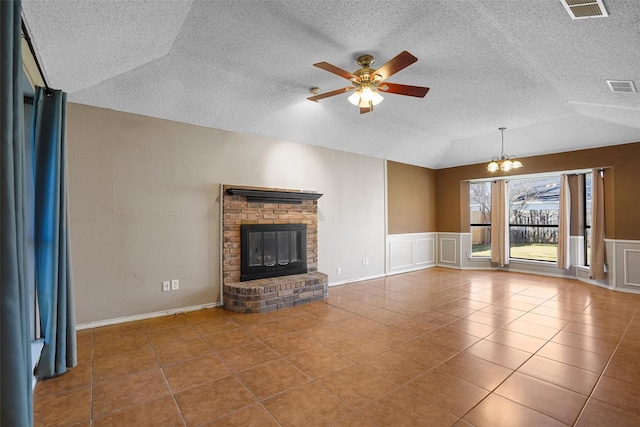 unfurnished living room featuring vaulted ceiling, visible vents, a fireplace, and tile patterned floors