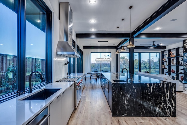 kitchen with a sink, modern cabinets, light wood-type flooring, high end range, and exhaust hood