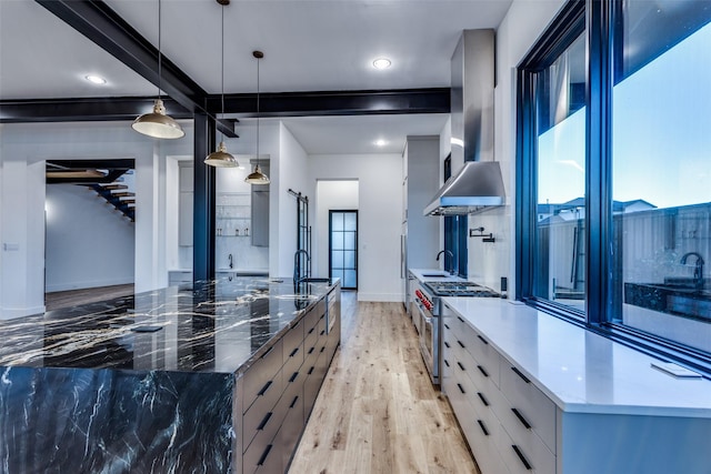 kitchen with light wood-type flooring, wall chimney range hood, modern cabinets, and stainless steel range