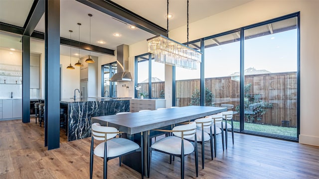 dining room featuring beamed ceiling, light wood-type flooring, and a wealth of natural light