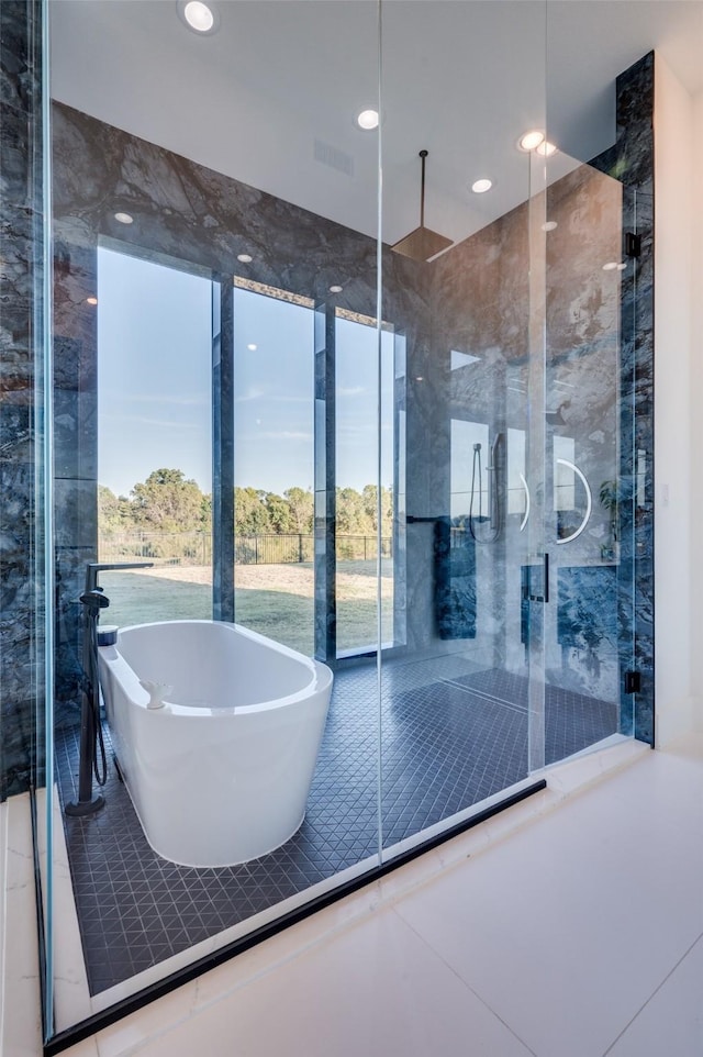 full bathroom featuring a shower, a wealth of natural light, visible vents, and a freestanding bath