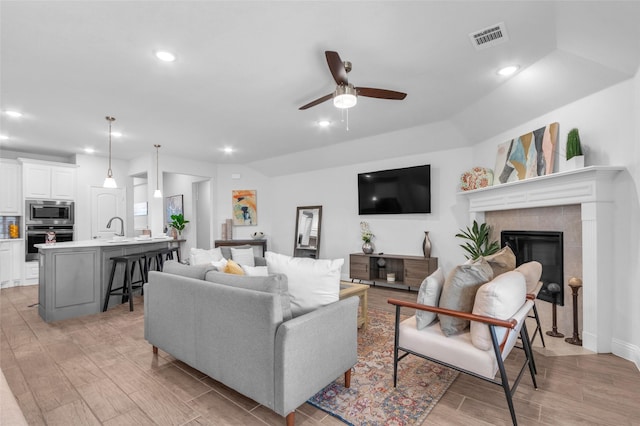 living area with a fireplace, recessed lighting, visible vents, a ceiling fan, and wood tiled floor