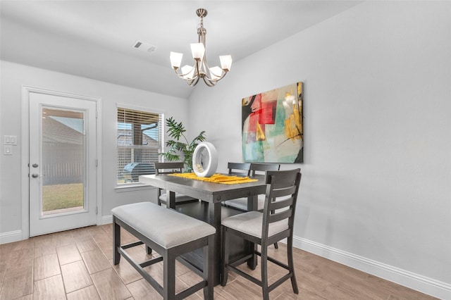 dining room with a notable chandelier, light wood finished floors, lofted ceiling, visible vents, and baseboards