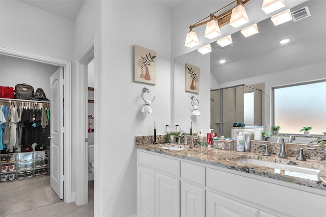 full bathroom featuring double vanity, a shower stall, visible vents, and a sink