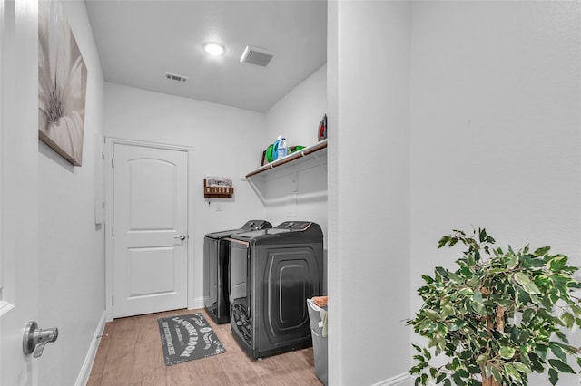 laundry room featuring laundry area, light wood finished floors, washing machine and clothes dryer, and visible vents