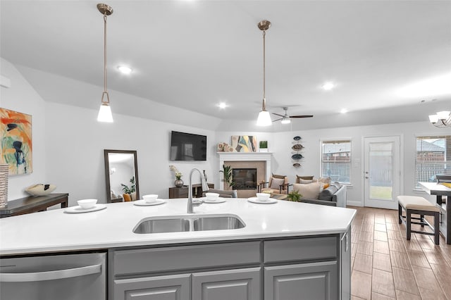 kitchen with a glass covered fireplace, gray cabinets, dishwasher, and a sink