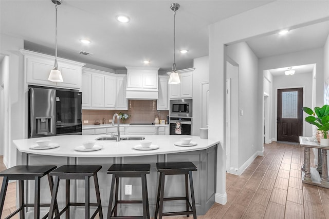 kitchen featuring tasteful backsplash, appliances with stainless steel finishes, a breakfast bar, light wood-type flooring, and a sink