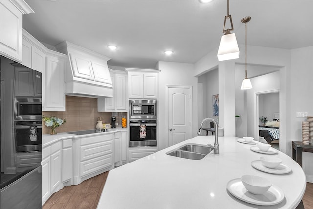 kitchen featuring black electric cooktop, wood finished floors, a sink, light countertops, and tasteful backsplash