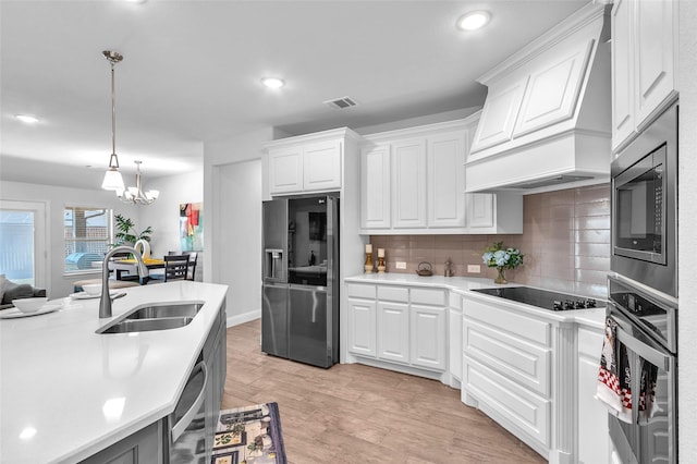 kitchen with stainless steel appliances, premium range hood, a sink, visible vents, and light countertops