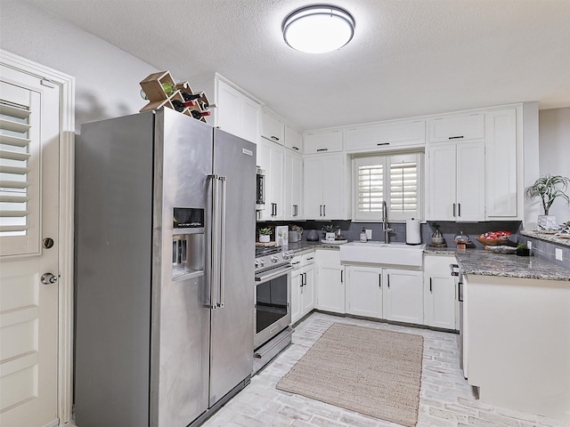 kitchen with white cabinets, brick floor, stainless steel appliances, and a sink