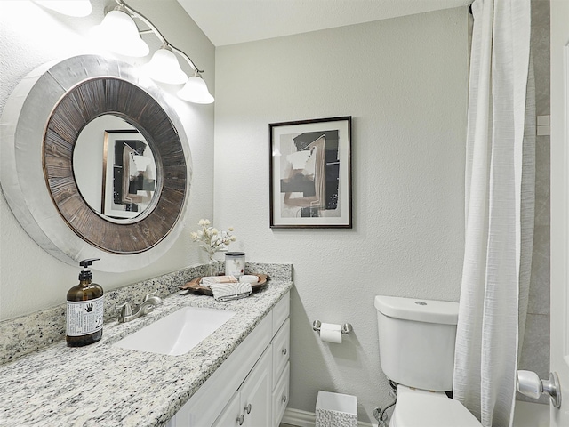 bathroom featuring a shower with curtain, a textured wall, vanity, and toilet