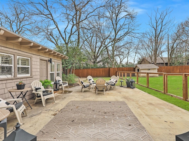 view of patio / terrace with a fenced backyard, an outdoor structure, and a fire pit