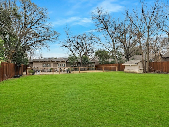 view of yard featuring a fenced backyard, a storage unit, and an outdoor structure