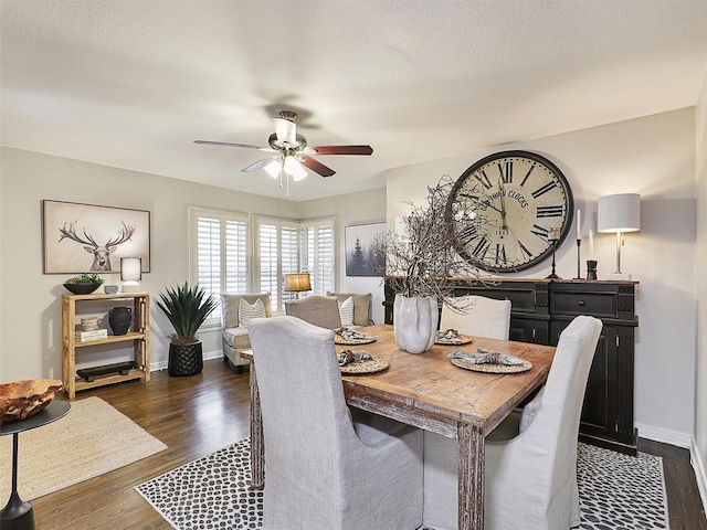 dining room featuring dark wood-type flooring, ceiling fan, a textured ceiling, and baseboards