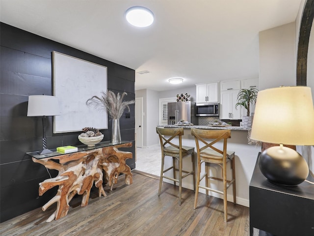 kitchen with stainless steel appliances, a breakfast bar area, light wood-style flooring, and white cabinets