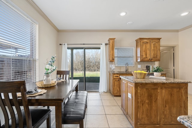 kitchen with crown molding, light tile patterned flooring, a sink, and a kitchen island