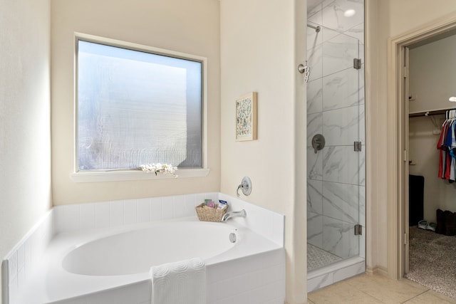 bathroom featuring tile patterned floors, a garden tub, a walk in closet, and a shower stall