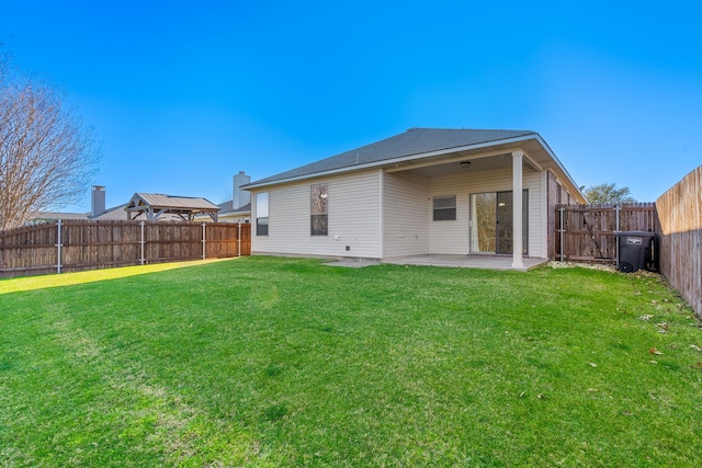 rear view of house featuring a fenced backyard, a lawn, and a patio