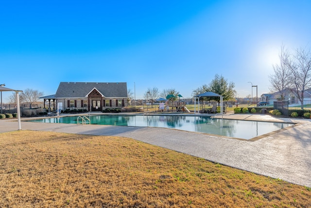 community pool featuring playground community, a patio, fence, and a lawn