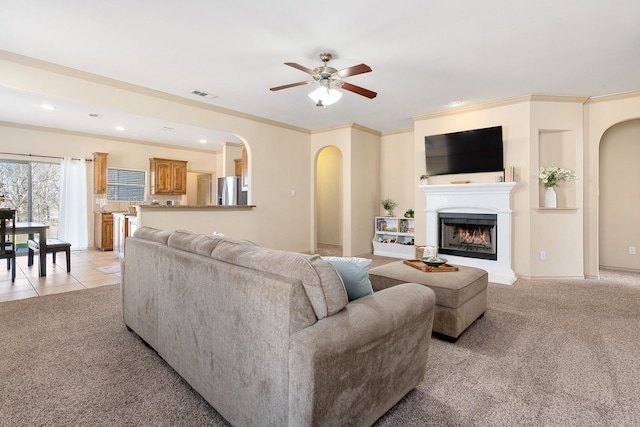 living area featuring a lit fireplace, light colored carpet, visible vents, and light tile patterned floors