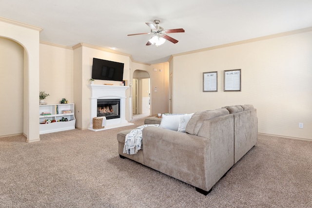 living room featuring arched walkways, a lit fireplace, ornamental molding, and carpet