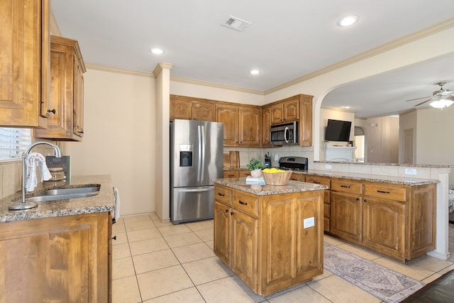 kitchen featuring a peninsula, light stone countertops, stainless steel appliances, and a sink