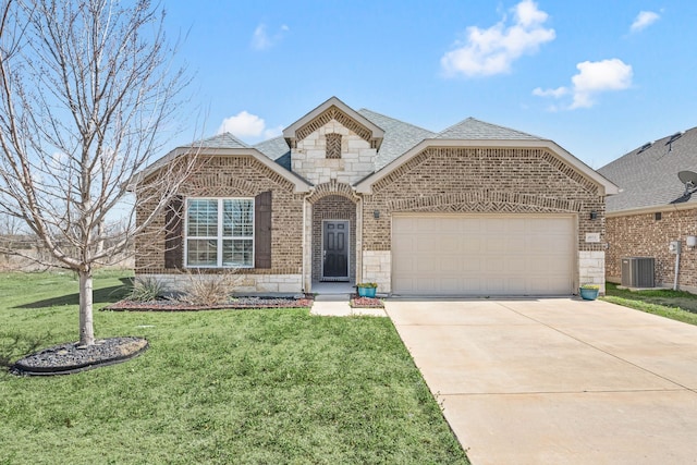 french country home with a shingled roof, a front lawn, concrete driveway, stone siding, and brick siding