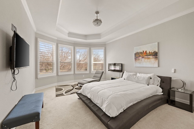 carpeted bedroom with a tray ceiling, baseboards, and ornamental molding