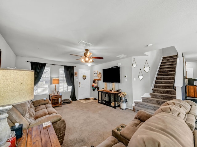 carpeted living room featuring a ceiling fan, visible vents, stairway, and baseboards